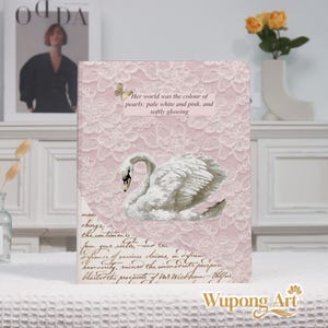 May include: A notebook with a pink lace pattern background and a white swan illustration. The text "Her world was the colour of pearls: pale white and pink, and softly glowing" is displayed. The notebook is branded with "Wupong Art".