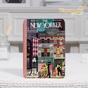 Könnte beinhalten: Ein dekorativer rechteckiger Gegenstand mit einem Vintage-Cover des Magazins The New Yorker vom 1. Juni 1946. Das Cover zeigt eine farbenfrohe Straßenszene mit Geschäften, einem Pferdewagen und dem Text "QUILTS & PILLOWS". Der Artikel hat einen rosa Rand.