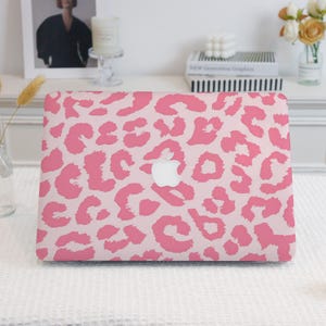 May include: Pink leopard print laptop skin with a white Apple logo.