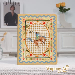 May include: A rectangular, cream-colored notebook with a watercolor illustration of a cowboy riding a horse. The design features a checkered background, floral accents, and a wavy blue border. The notebook is decorated with the text "Wupong Art".