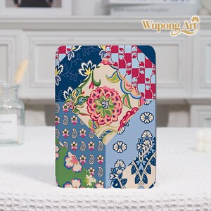 Può includere: Una custodia rettangolare per tablet caratterizzata da un vivace design patchwork con vari motivi, tra cui disegni floreali, stampe paisley e una griglia di ciliegie rossa e bianca. La tavolozza dei colori comprende tonalità di blu, rosa, verde e crema.