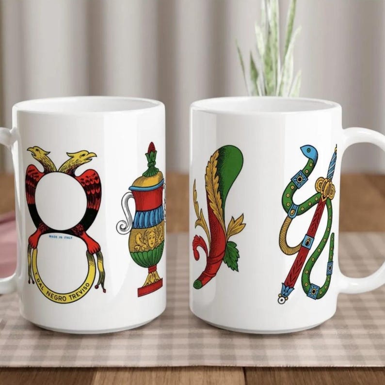 Two white ceramic mugs with colorful illustrations on them, placed on a checkered surface.