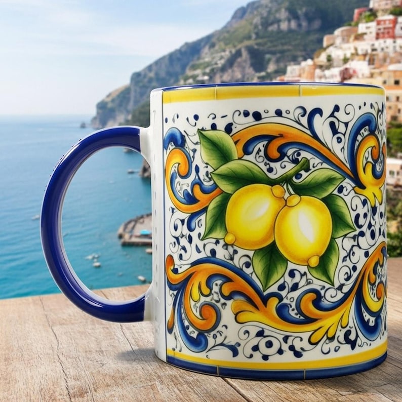 Peut inclure: Une tasse en c&eacute;ramique orn&eacute;e d'une illustration de citrons jaunes vifs avec des feuilles vertes, entour&eacute;e de motifs complexes de volutes bleues et jaunes. La tasse poss&egrave;de une anse bleu fonc&eacute; et un bord assorti, sur un fond c&ocirc;tier.