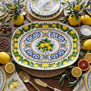May include: An oval ceramic serving platter featuring a central cluster of yellow lemons with green leaves, surrounded by a decorative blue and yellow scrollwork border and an outer rim pattern of lemons and foliage on a white background.
