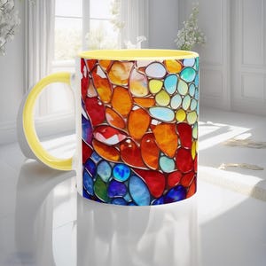 May include: A ceramic mug featuring a vibrant, multi-coloured mosaic pattern of rounded shapes in shades of red, orange, yellow, and blue. The mug has a bright yellow handle and a matching yellow interior rim, creating a bold contrast against the design.
