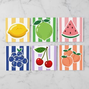 Könnte beinhalten: Ein Set aus sechs quadratischen Untersetzern mit Fruchtillustrationen auf gestreiften Hintergründen. Die Motive zeigen eine gelbe Zitrone, eine grüne Limette, ein rosa Wassermelonenstück, blaue Heidelbeeren, rote Kirschen und orangefarbene Pfirsiche.