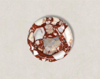 Op de afbeelding: Een ronde, decoratieve asbak met een uniek patroon. De asbak heeft een mix van rode, witte en grijze kleuren, wat een marmer effect creëert. Het ontwerp is cirkelvormig met een gebogen rand. Diameter: ongeveer 10 cm.