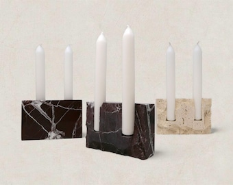 May include: Three marble candle holders with white candles. The candle holders are rectangular and feature a dark brown and white marble pattern, and a beige stone. Each holder has space for two candles.