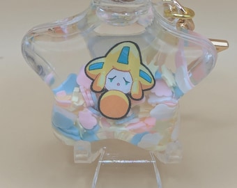 May include: A clear, star-shaped glass bottle with a cork stopper. The bottle features a cartoon character sticker and is filled with colorful confetti. A gold-colored ring is attached to the bottle. The bottle is displayed on a clear stand.