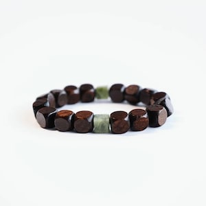 May include: A dark brown wooden bracelet with a single green stone bead.