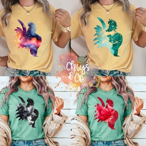 May include: Four different t-shirts featuring a watercolour rooster design. The rooster is depicted in a variety of colours, including blue, green, red, and black. The shirts are all a light green colour.