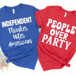 May include: Two t-shirts with a patriotic theme. The blue shirt says "Independent Thinker Voter American". The red shirt says "People Over Party" with a star in the middle of the word "Over".