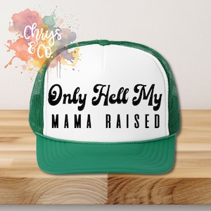 Puede incluir: Una gorra de camionero blanca y verde con el texto "Only Hell My Mama Raised" en letras cursivas negras.