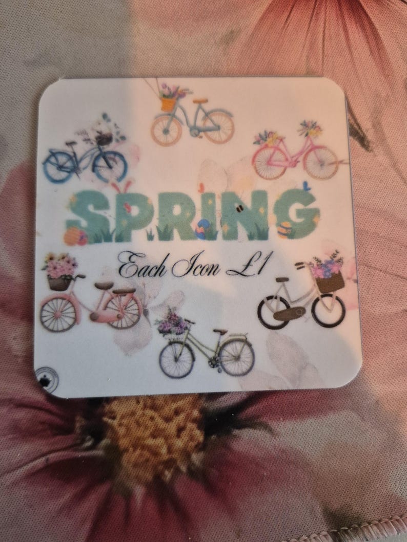 May include: A white coaster with a spring theme, featuring bicycles with flower baskets and the word "SPRING" in green and blue. The text "Each Icon L1" is also present.
