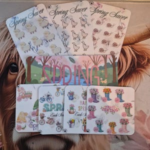 May include: A collection of spring-themed cards with various designs. Some cards feature sheep, ducks, and snails, while others display gnomes, bicycles, and flower-filled boots. The word "SPRING" is prominently displayed on several cards.