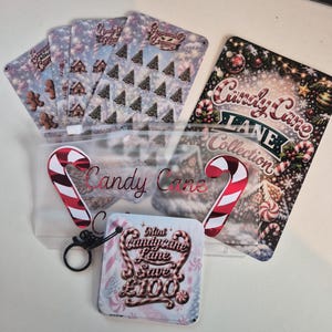 May include: A set of Candy Cane Lane collection items including a translucent zipper pouch with candy cane graphics, several patterned cards featuring gingerbread men and trees, and a square card with the text Mini Candy Cane Lane Save £100.