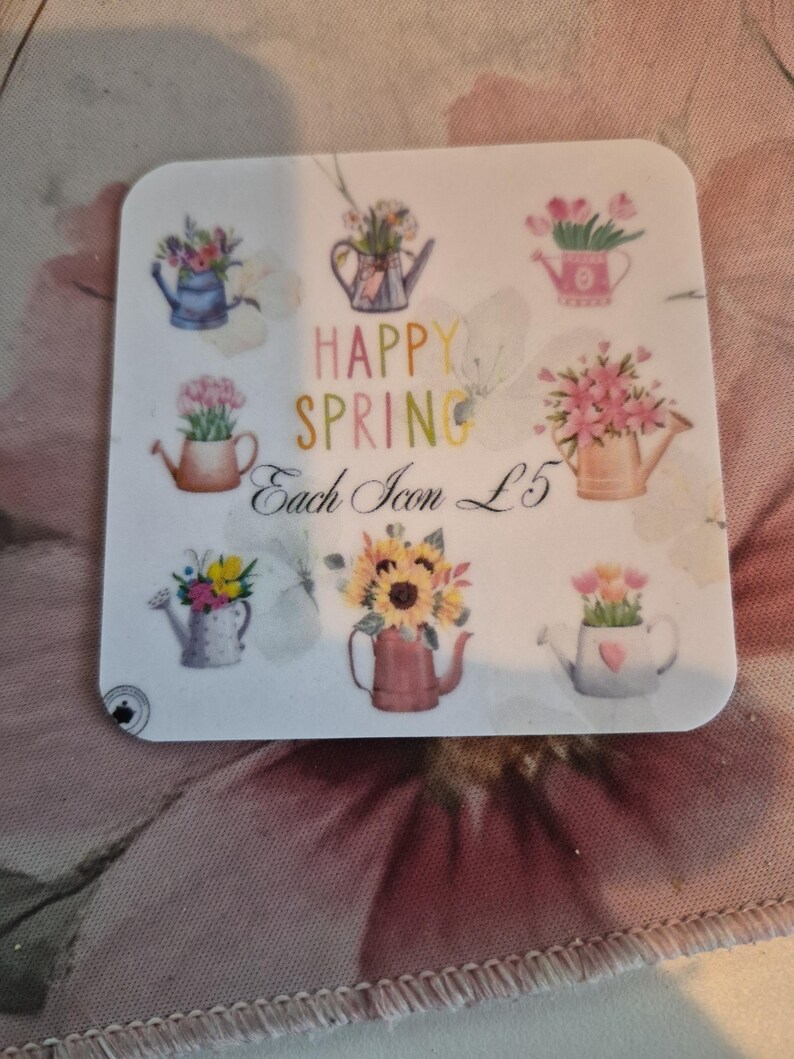 May include: A square sticker featuring watercolor illustrations of watering cans filled with flowers. The text "HAPPY SPRING" is displayed in colorful letters. Each icon is priced at &pound;5.