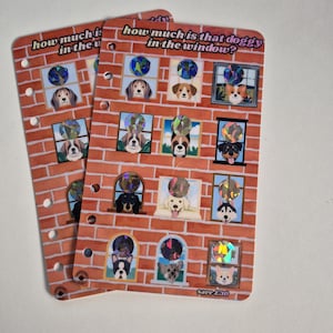 May include: Two rectangular planner inserts with a brick wall pattern and the text "how much is that doggy in the window?" featuring various dog breeds in windows, each topped with a circular holographic sticker. The pages have punched holes.