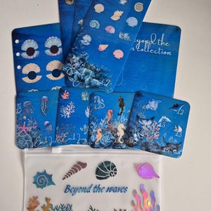 May include: A collection of blue ocean-themed planner inserts and a translucent zipper pouch. The items feature illustrations of seashells, seahorses, jellyfish, and stingrays. The pouch displays the text Beyond the waves and holographic coral designs.