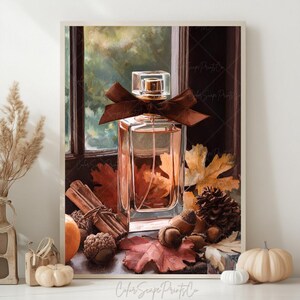 May include: A rectangular perfume bottle with a brown bow, set against a backdrop of fall foliage. The image includes cinnamon sticks, acorns, and pumpkins, creating a seasonal autumn theme. The bottle is filled with a light-colored liquid.