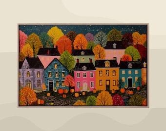 May include: A framed painting depicts a colorful autumn scene. Several houses in various colors, including pink, blue, and yellow, are nestled among trees with vibrant orange, red, and yellow foliage. Pumpkins are scattered in the foreground.