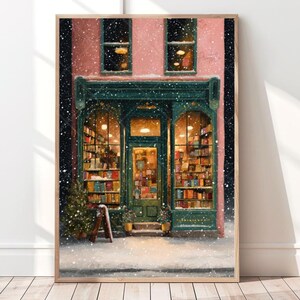 May include: A framed print of a cozy bookstore scene in winter. The building has a green facade and is filled with books. Snow falls around the building, and the windows are lit with warm light. A small Christmas tree is visible.
