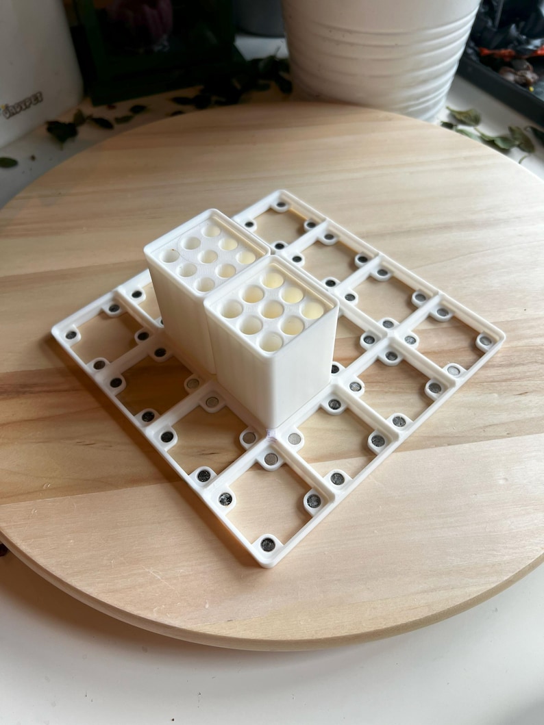 Puede incluir: Organizador de pl&aacute;stico blanco con m&uacute;ltiples compartimentos para guardar objetos peque&ntilde;os. El organizador est&aacute; formado por dos secciones apilables con agujeros circulares y una base con un patr&oacute;n de cuadr&iacute;cula.