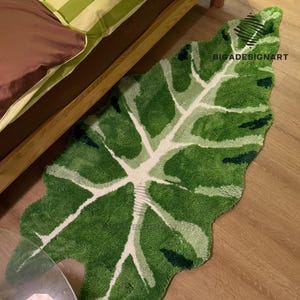 May include: A green and white leaf-shaped rug with a textured surface. The rug is made of a soft, plush material and has a unique design.