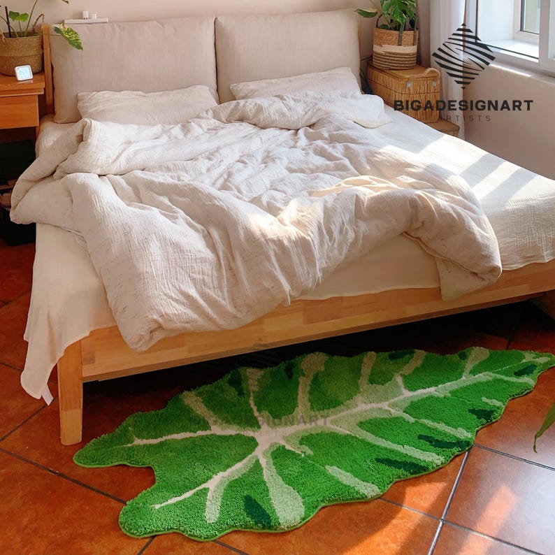 May include: A green leaf-shaped rug with a white center, placed under a bed with white bedding and a wooden frame.