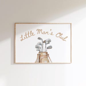 Puede incluir: Impresi&oacute;n enmarcada con una ilustraci&oacute;n en acuarela de una bolsa de golf llena de palos. Las palabras "Little Man's Club" est&aacute;n escritas en una fuente cursiva encima de la bolsa de golf. La paleta de colores es neutra, con tonos beige y grises.