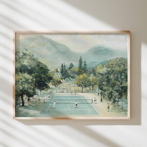 Könnte beinhalten: Gerahmtes Aquarellgemälde einer Tennisplatzszene. Der Platz ist hellblau mit einem Netz, umgeben von Bäumen und Bergen im Hintergrund. Das Gemälde hat eine weiche, gedämpfte Farbpalette.