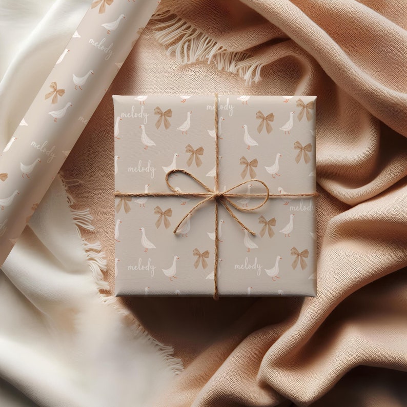 May include: A gift box wrapped in brown paper with a white goose and bow pattern. The paper has the word "melody" repeated on it. The box is tied with twine and has a brown bow.