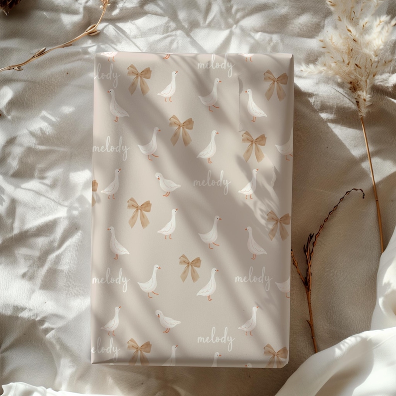 May include: Beige wrapping paper with a repeating pattern of white geese and brown bows. The text "melody" is repeated throughout the paper.