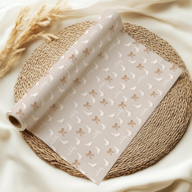 May include: A roll of beige wrapping paper with a repeating pattern of white geese and brown bows. The paper has the text "perfectly" repeated throughout the pattern.