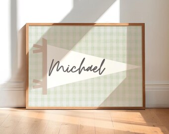 May include: A framed wall art piece featuring a pennant design with the name "Michael" in a cursive font. The pennant is cream-colored with a light green gingham background. The frame is made of wood.