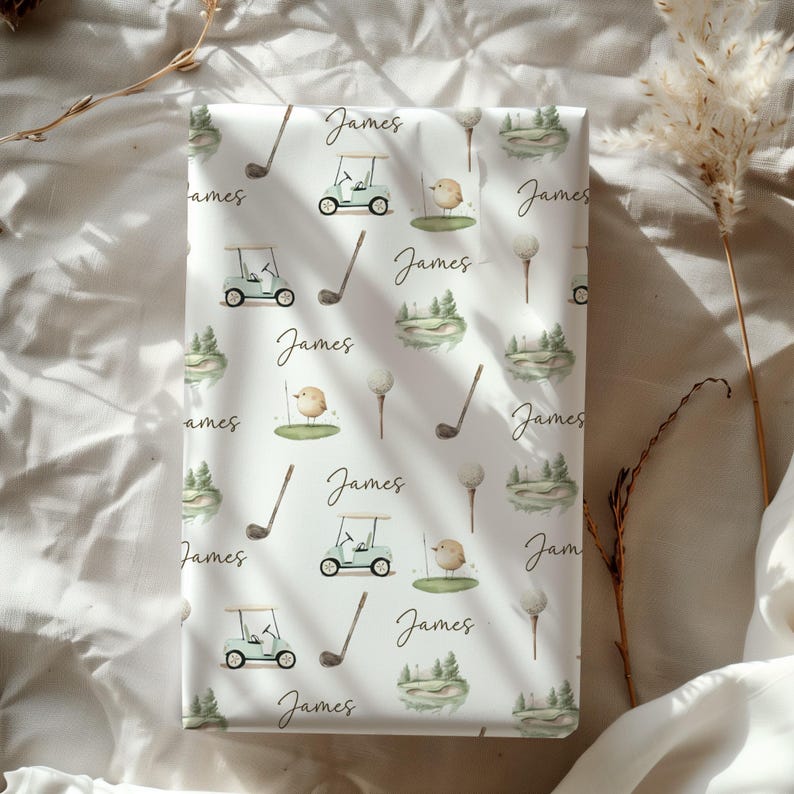 May include: White wrapping paper featuring a golf-themed pattern. The design includes golf carts, golf clubs, golf balls, small birds, and miniature golf course scenes. The name "James" is written in a script font throughout the design.