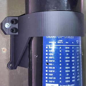 May include: A black UV sterilizer system with a blue label that reads "SMART UV STERILIZER". The system is mounted on a wooden surface with a black bracket and screws. White and black pipes are also visible.