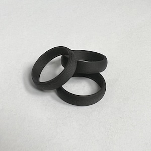 Puede incluir: Tres anillos de silicona negros apilados uno encima del otro.