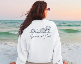 May include: White sweatshirt with a graphic of seashells and a starfish on the back. The text "Summer Vibes" is printed below the graphic.