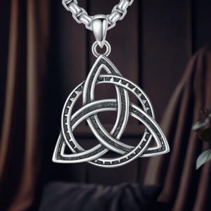 May include: Silver-toned pendant necklace featuring a Celtic knot design. The pendant is shaped like a triangle with three interlocking circles.