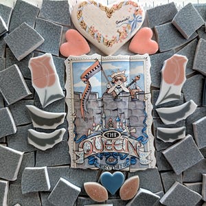 May include: A mosaic of ceramic tiles featuring a heart-shaped piece with floral designs and the name "Annie". Other tiles include pink hearts, tulip shapes, and a central piece depicting a queen with the text "THE QUEEN of EVERYTHING".