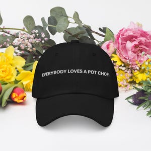 May include: A black baseball cap with white embroidered text that reads "EVERYBODY LOVES A POT CHOP."