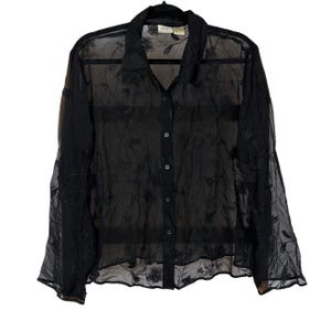 May include: A black long-sleeved button-down shirt made of a sheer, translucent fabric. The garment features an intricate, tonal floral embroidery pattern throughout the entire piece, a standard collar, and a front button closure with matching buttons.