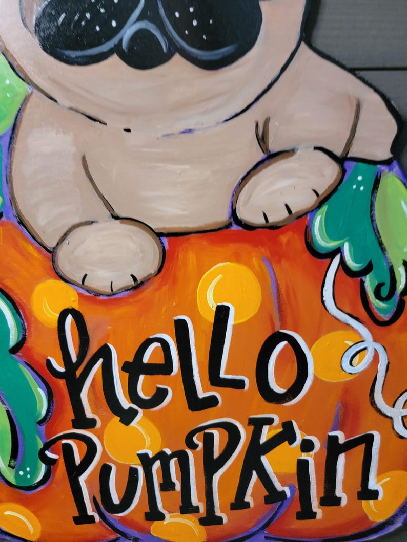 May include: A hand-painted wooden sign featuring a pug dog sitting on an orange pumpkin. The sign has the words "hello Pumpkin" in black and white lettering. The pumpkin has yellow polka dots and green leaves.