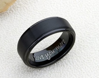 May include: A black tungsten carbide ring with a beveled edge and a brushed finish. The inside of the ring is engraved with the words "I love you more".