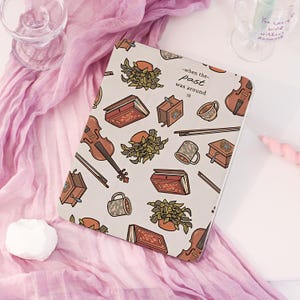 May include: A rectangular tablet case with a light beige background featuring a repeating pattern of brown violins, bows, vintage books, coffee grinders, mugs, and potted plants. The text -when the- past was around :| is printed in black.