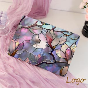 May include: A laptop case with a stained-glass floral design in shades of purple, pink, and blue. The design features magnolia flowers and leaves. The Apple logo is visible on the case. The word "Logo" is written in a script font.