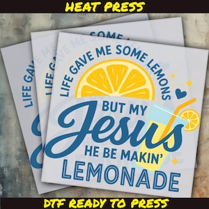 May include: A stack of DTF (Direct to Film) heat transfer sheets with a design featuring a lemon slice, a glass of lemonade, and the text "Life Gave Me Some Lemons But My Jesus He Be Makin' Lemonade". The design is in yellow and blue.