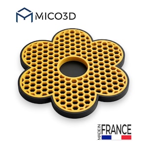 May include: A flower-shaped trivet with a black outer border and a yellow interior featuring a honeycomb pattern. The text MICO3D appears at the top, and the text MADE IN FRANCE with a blue, white, and red flag icon appears at the bottom.