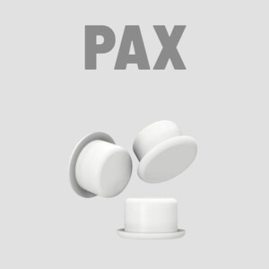 K&ouml;nnte beinhalten: Vor einem hellgrauen Hintergrund werden wei&szlig;e, zylindrische Objekte mit flachen Krempen, die an Miniatur-Zylinderh&uuml;te erinnern, gezeigt. Das Wort "PAX" ist in grauen Blockbuchstaben dar&uuml;ber gedruckt. Die Objekte sind dynamisch angeordnet, einige scheinen zu schweben.